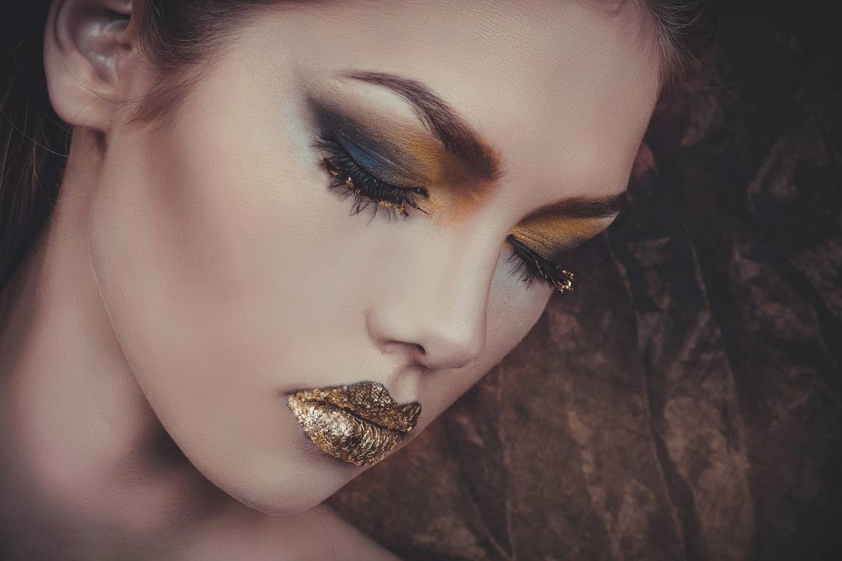 Professional makeup artist applying high glam makeup with brushes and shimmer products on model's face
